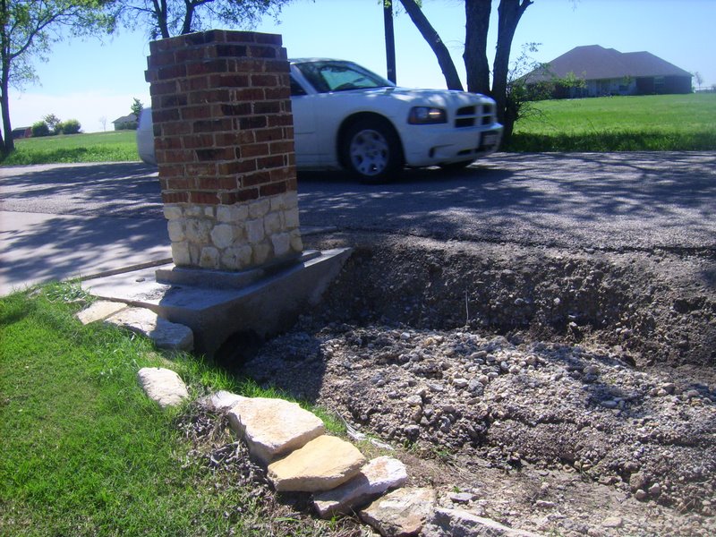 The ditch caved in from the water rushing over the road
